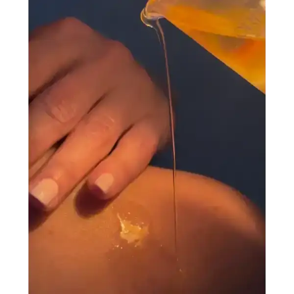 Warm massage candle oil being poured onto skin